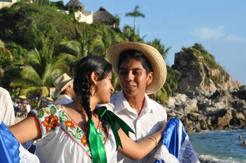 Young boy and girl in folkloric costumes dancing at Playa Manzanillo, Puerto Escondido, Mexico