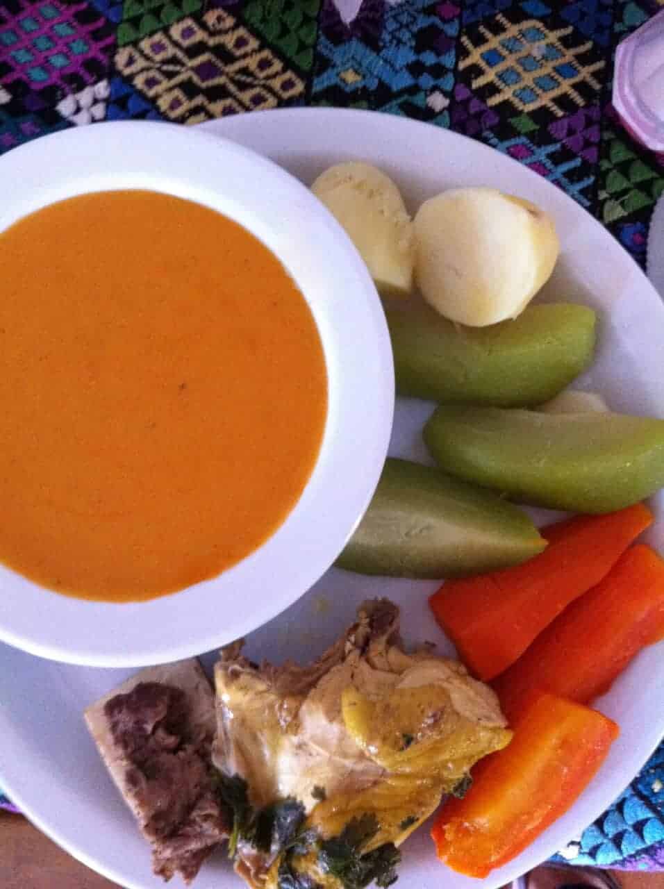 Bowl of pulique de pollo Guatemalteco with vegetables and chicken on the side. 