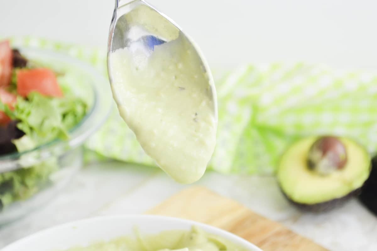 Avocado dressing dropping from a spoon.