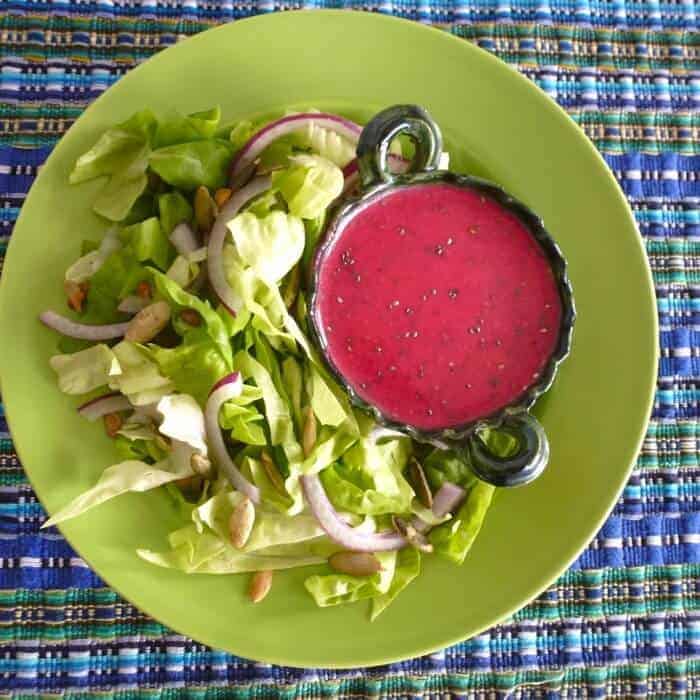 Healthy prickly pear and chia salad dressing on a green salad in a lime green bowl. 