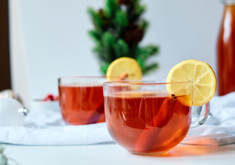 Hot Bourbon Toddy with lemon garnish on a white table.