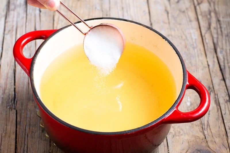 Adding sugar to fruit juice to make Guatemalan hot fruit punch. 