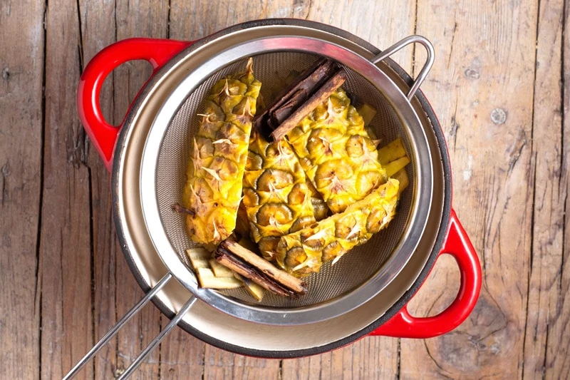 Straining the husk of a pineapple for extra flavour in ponche de frutas.