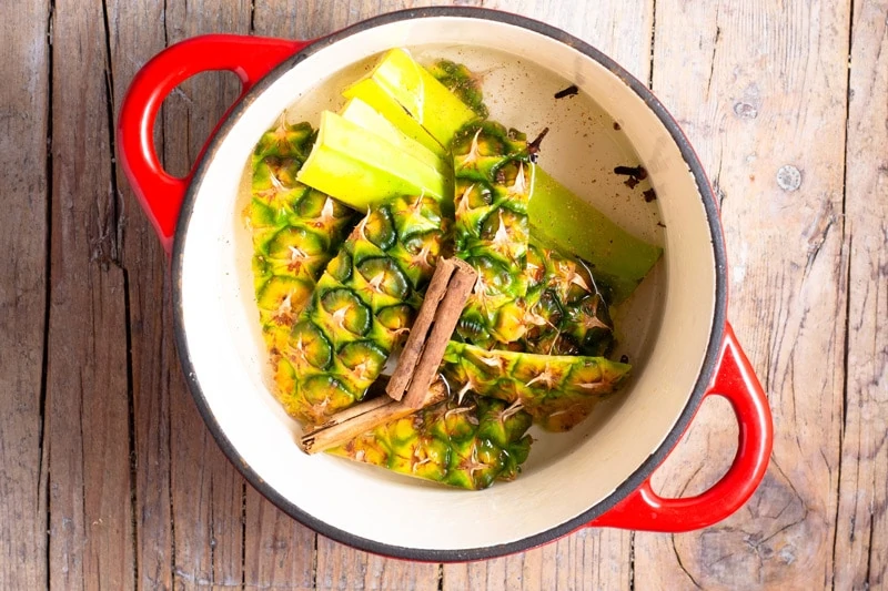 Pineapple cooking in a red pot for Ponche de Frutas.