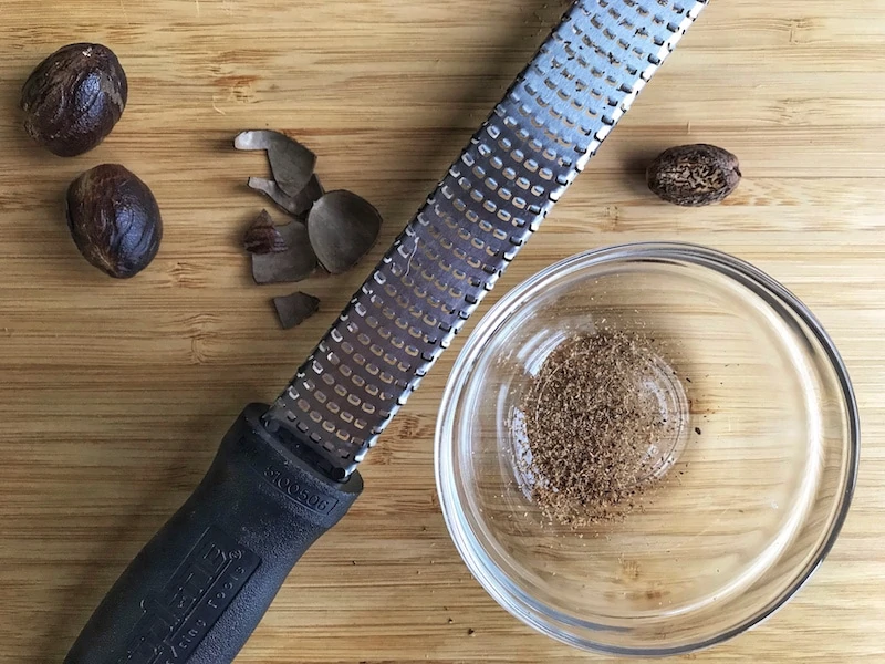 A microplane zester/grater and fresh nutmeg with a small bowl. 