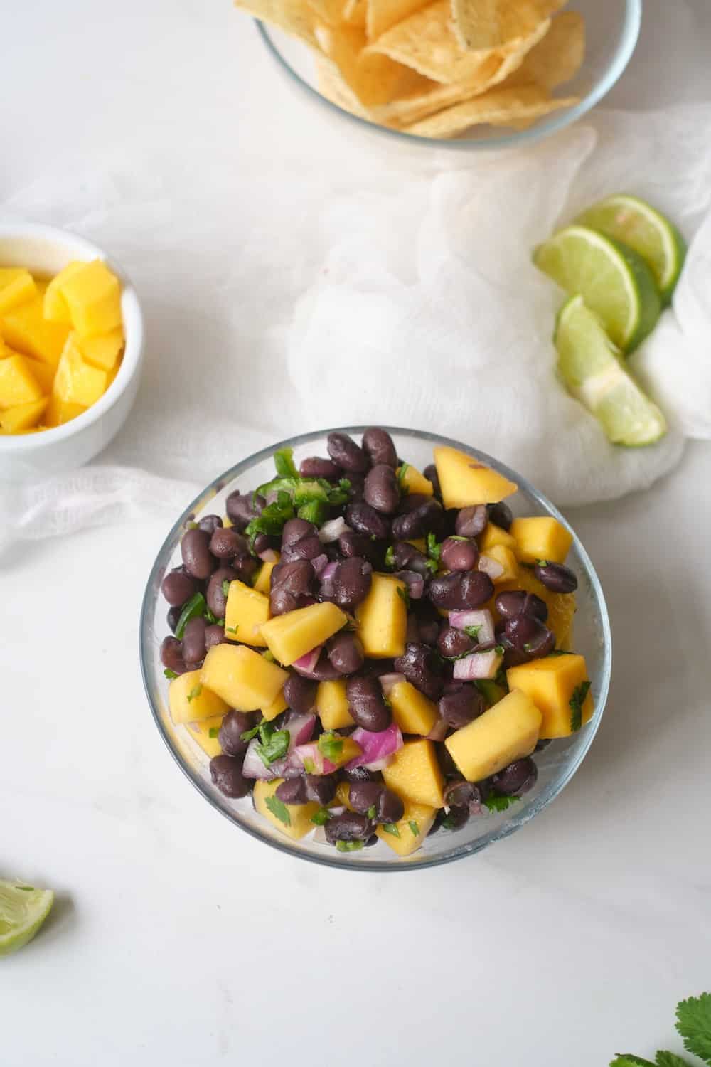 Overhead shot of black bean mango salad in a clear bowl. 