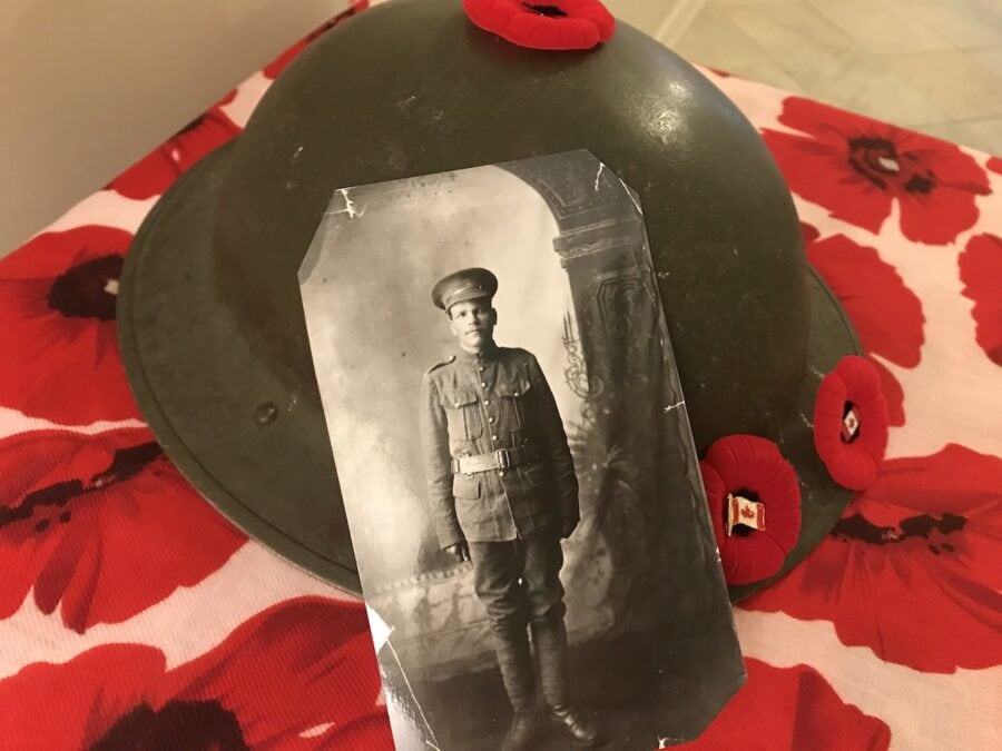 Photo of Peter Bielly in WWI uniform in front of a helmet and poppies.