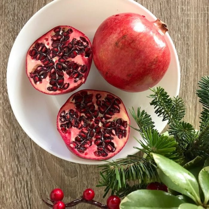 Cut pomegranates on a table with greenery at Christmas.