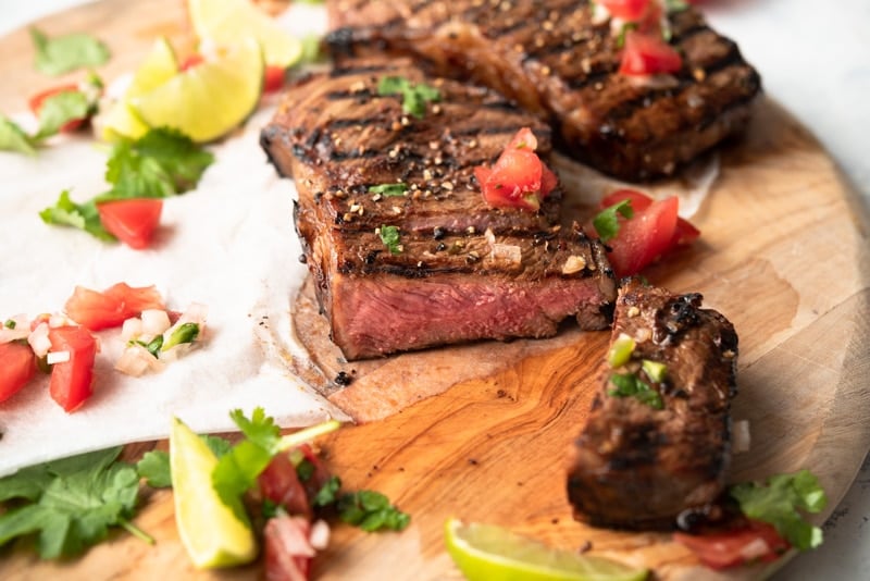 Grilled Steaks on a wooden board with Salsa Fresca. 