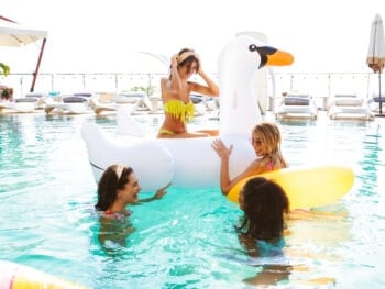Group of women in a swimming pool with inflatable toys enjoying a girlfriends getaway together.