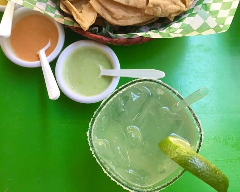 Margarita and taco chips on a green table in Mexico. 