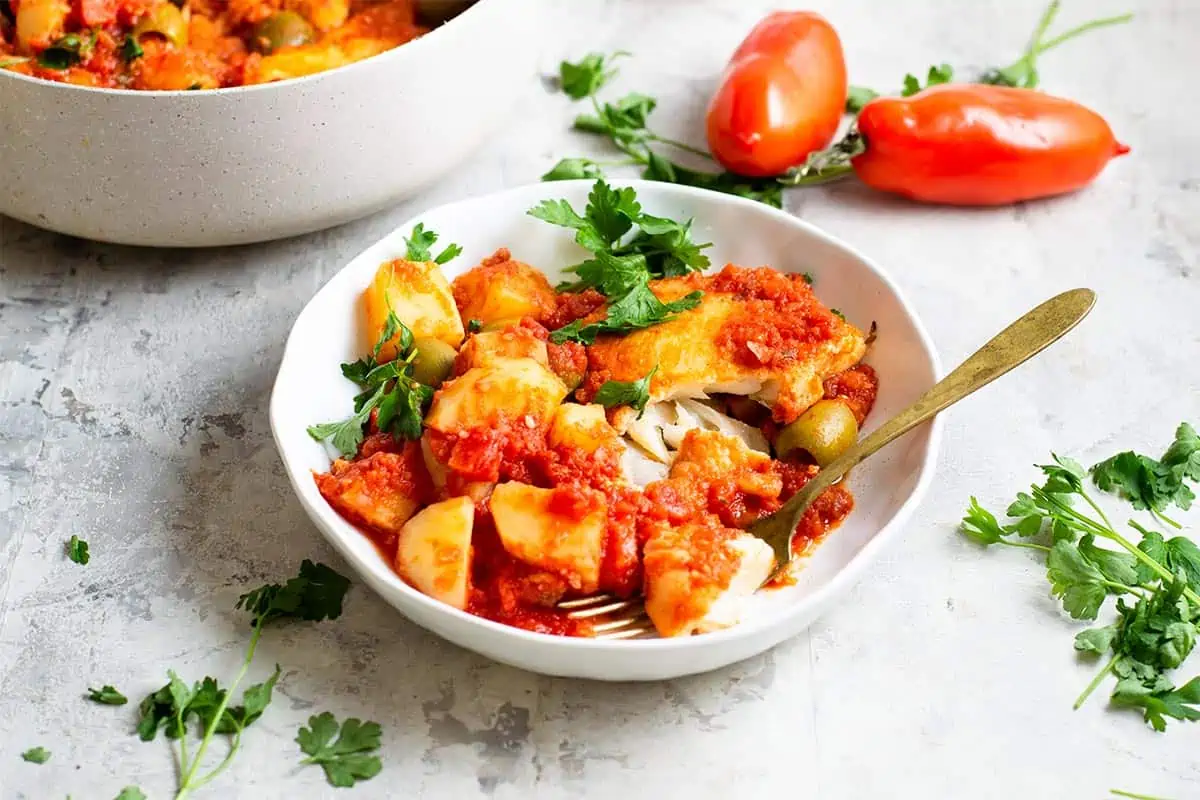 Bacalao a la Vizcaina in a white bowl with a spoon.