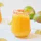 Sparkling mango cocktail on a white table.