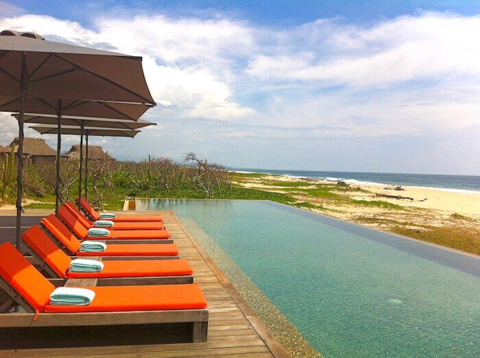 Swimming pool flanked by orange chairs at Hotel Escondido Puerto Escondido, Oaxaca. 