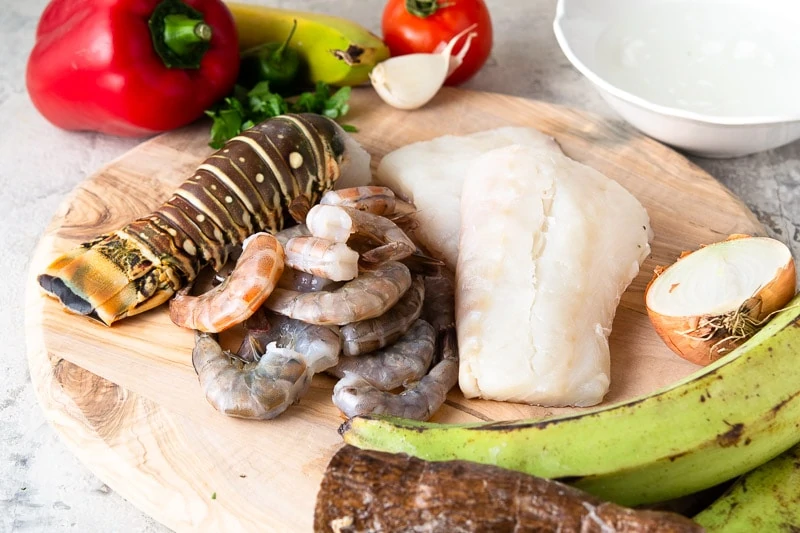 Ingredients for Tapado - Guatemalan seafood soup with coconut milk on a wooden board.