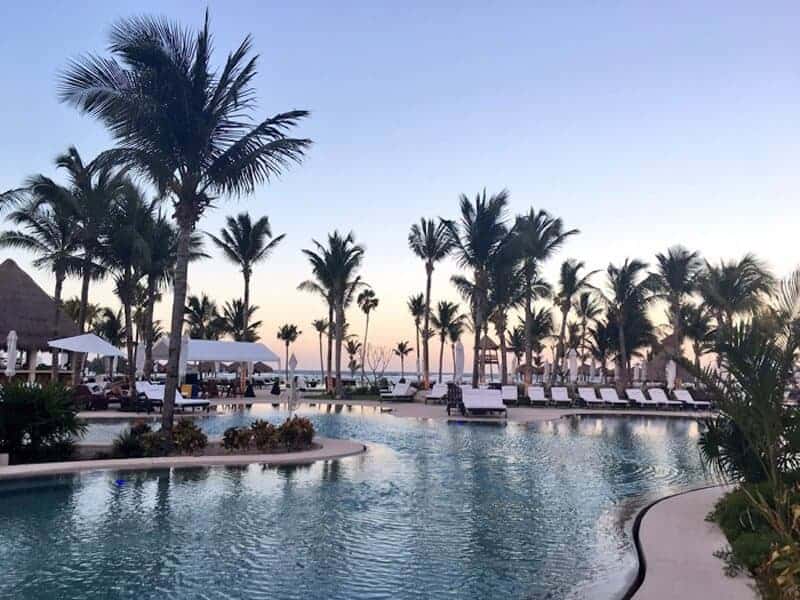 View of the swimming pool with palm trees at Secrets Akumal Riviera Maya. (Credit TheDownLo)