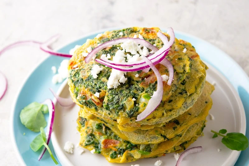 Serve Tortitas de Berro - Watercress Pancakes with crumbled dry cheese and slivers of red onion