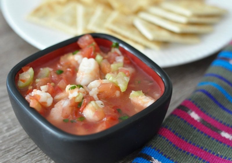 Guatemalan ceviche or fresh shrimp cocktail in a black bowl with saltines. 