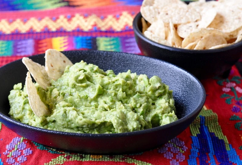 Easy Guatemalan Guacamole in an earthen bowl on a Mayan weaving.