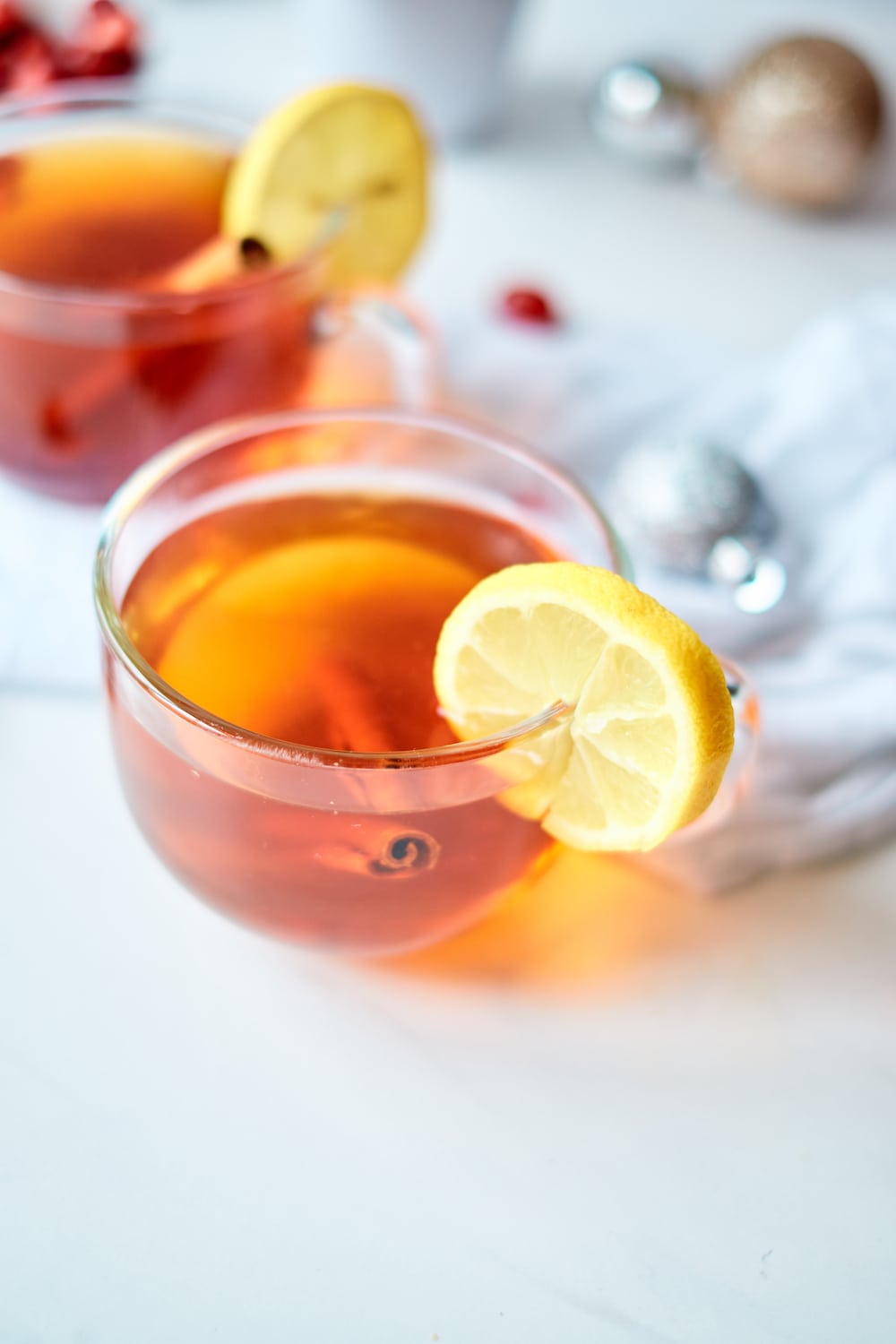 A clear mug of hot bourbon toddy with lemon on a table. 