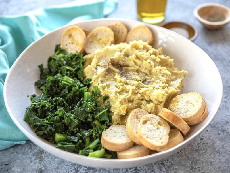 Pure di fave e cicorie in a white bowl with crostini. 