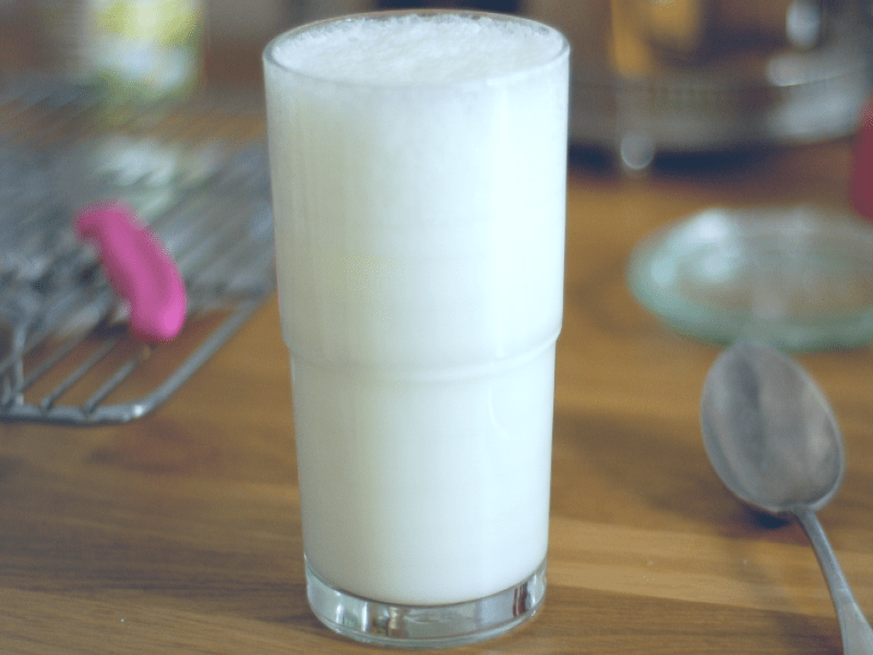 A glass of Ayran on a wooden table.