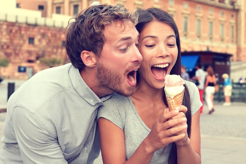 a couple eating a double scoop of ice cream. 