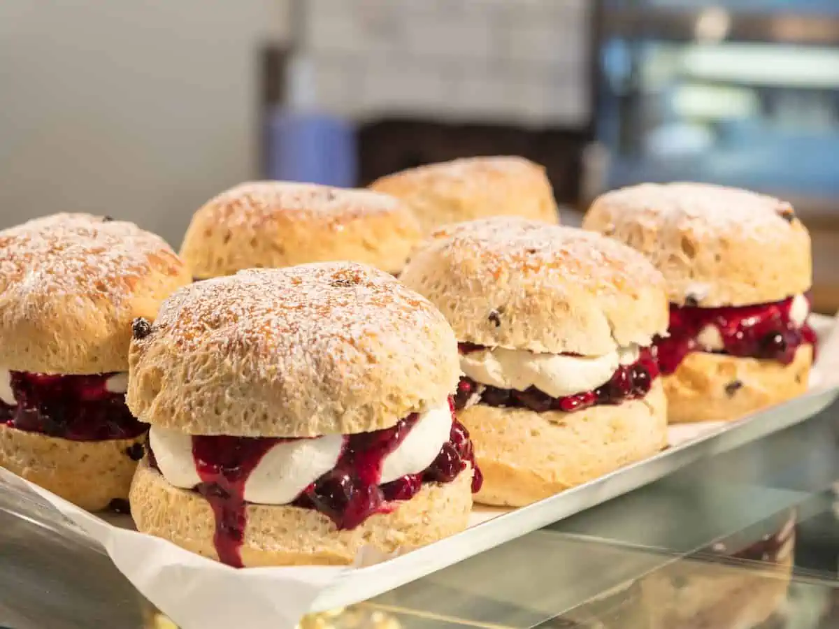 Six scones with clotted cream in a London bakery window.