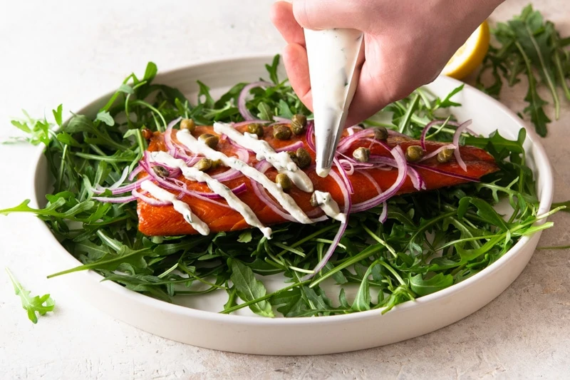 A person's hand piping with horseradish cream.