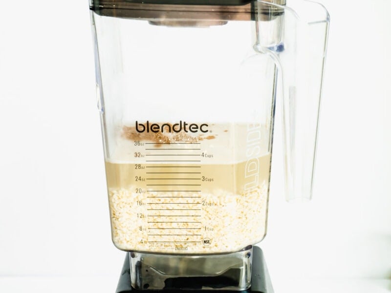 A blender with the ingredients for oat milk - oats, water and spices
