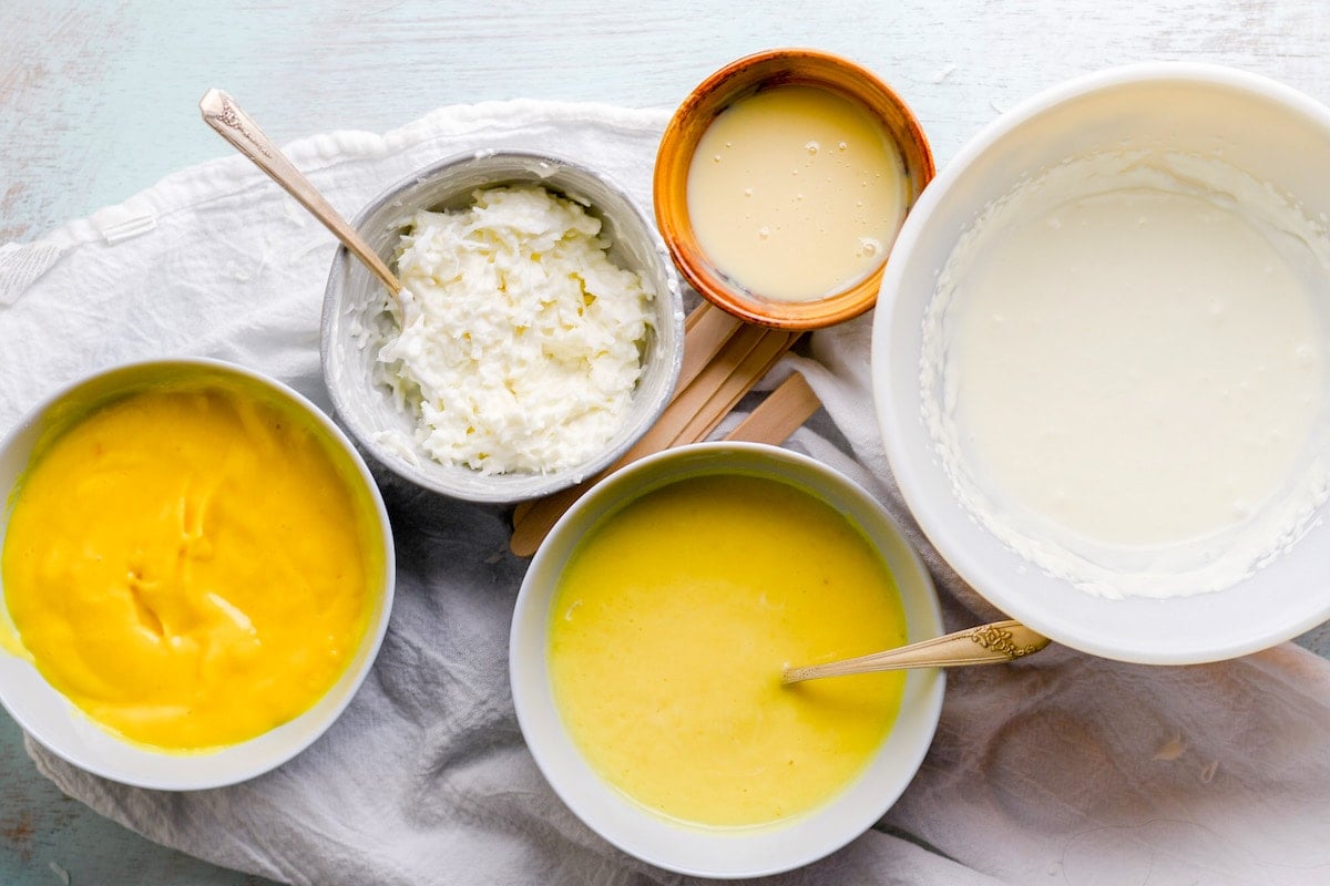 A bowl of mango puree, condense milk, coconut, coconut milk on a wooden board. 