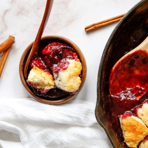 skillet with plum cobbler and a bowl of plum cobbler