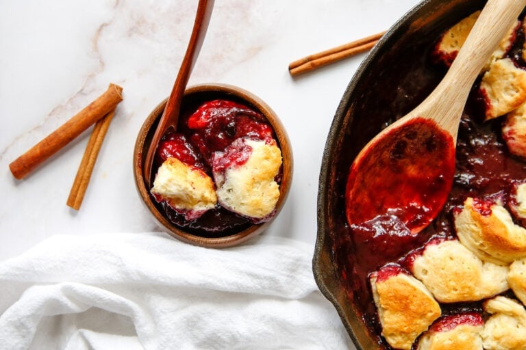 skillet with plum cobbler and a bowl of plum cobbler