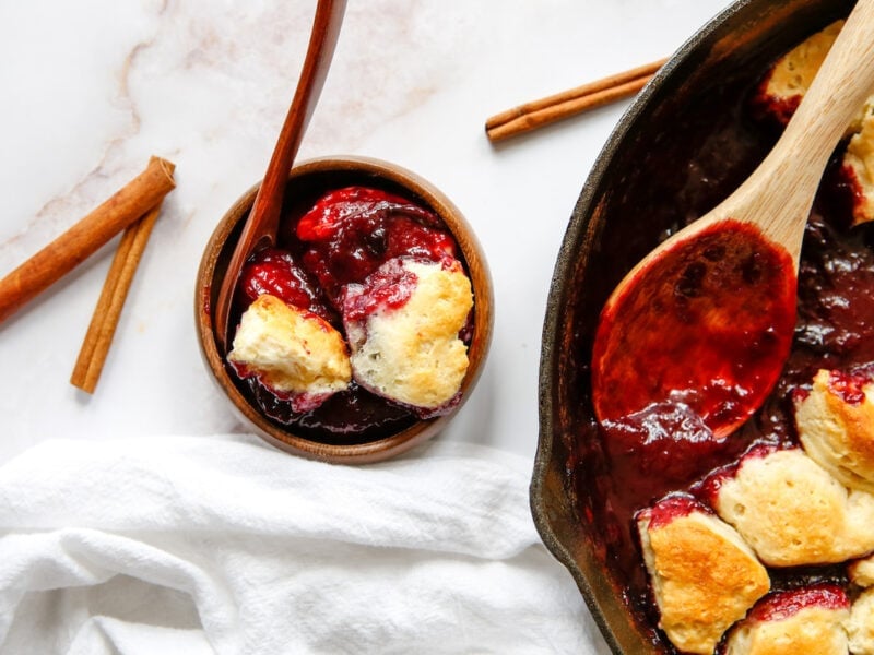 skillet with plum cobbler and a bowl of plum cobbler 