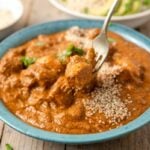 Pepian de pollo Guatemalan chicken stew in a blue bowl on a table.