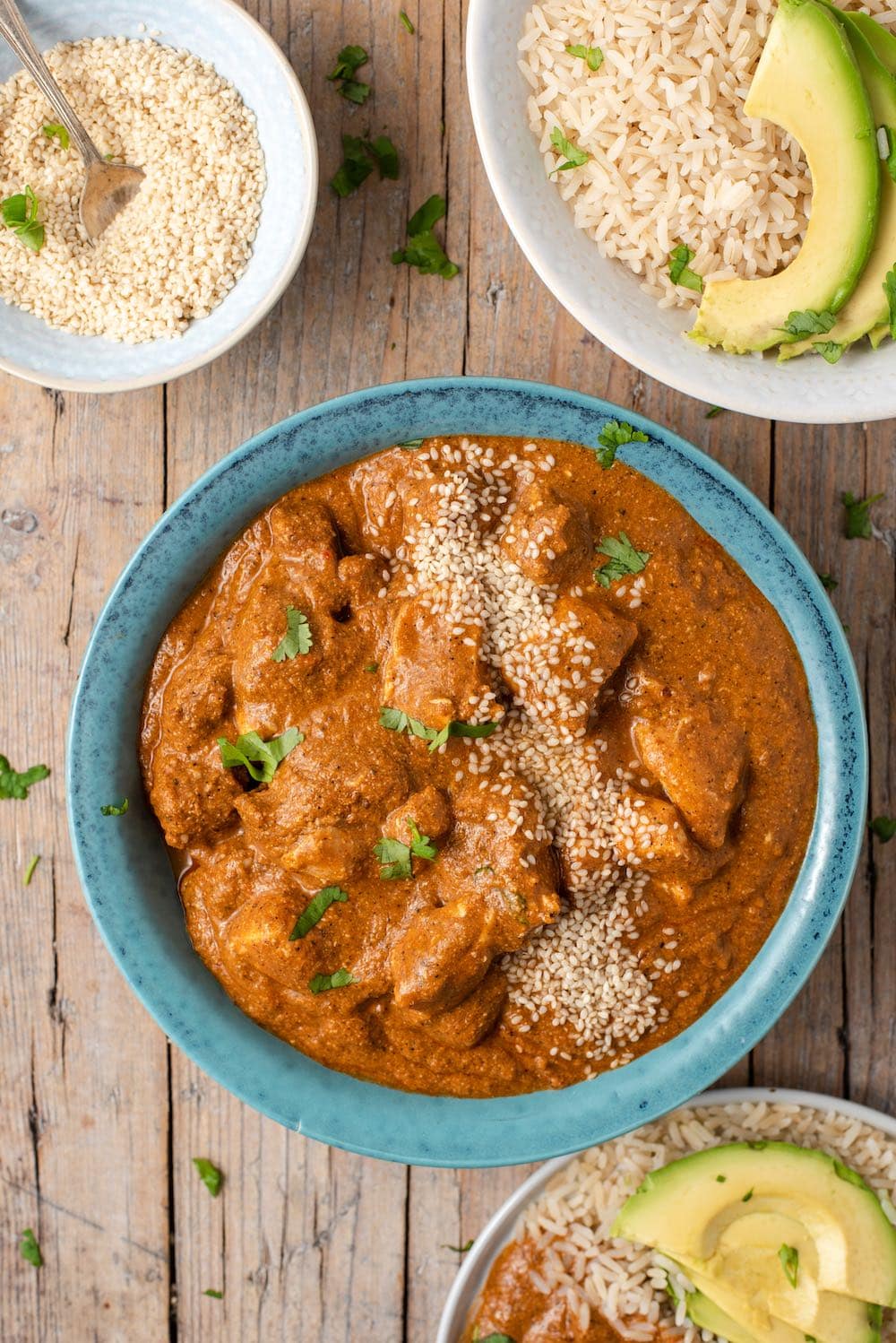 Overhead shot of Guatemalan chicken pepian in a blue bowl with rice and avocado.