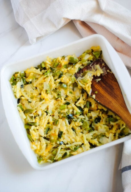 Poblano breakfast casserole mixture being poured into a white baking dish.