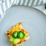 Spanish breakfast casserole on a plate topped with jalapeno and avocado.