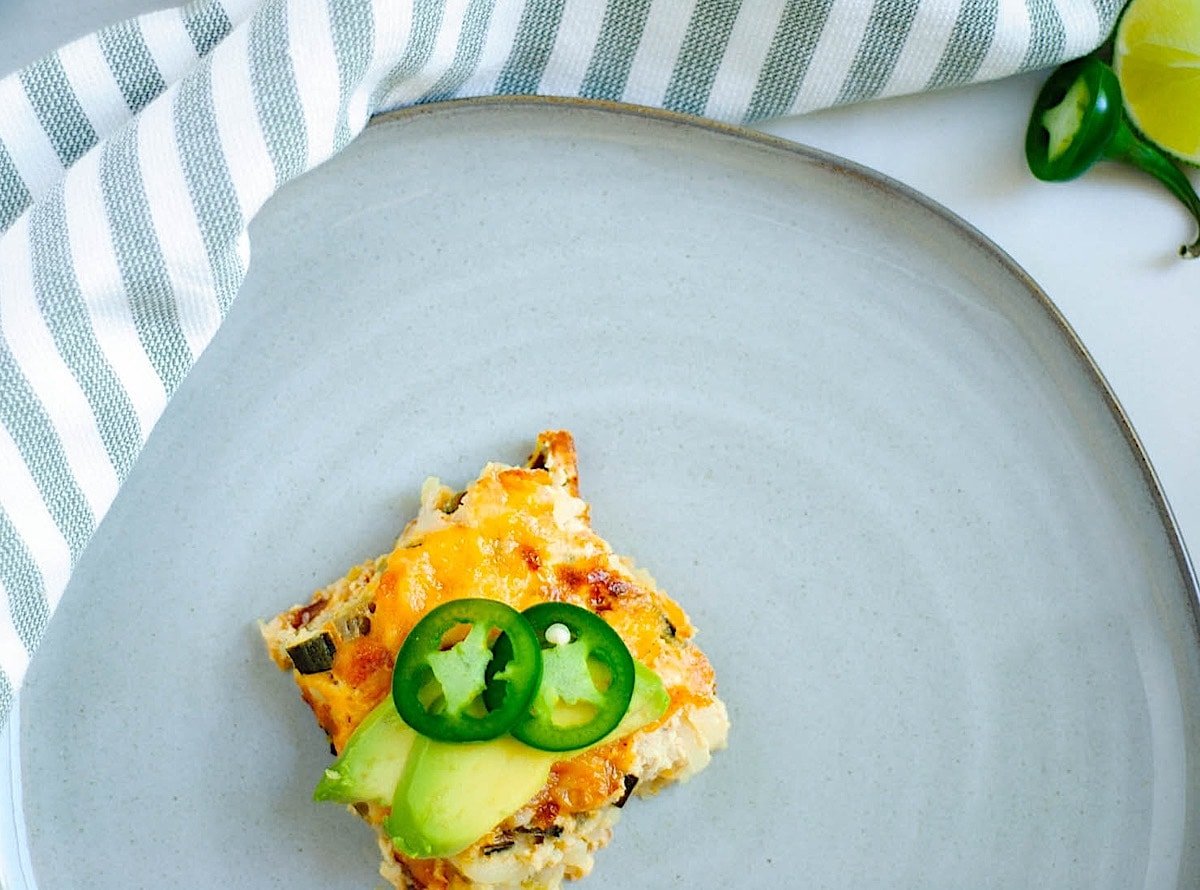 Spanish breakfast casserole on a plate topped with jalapeno and avocado.