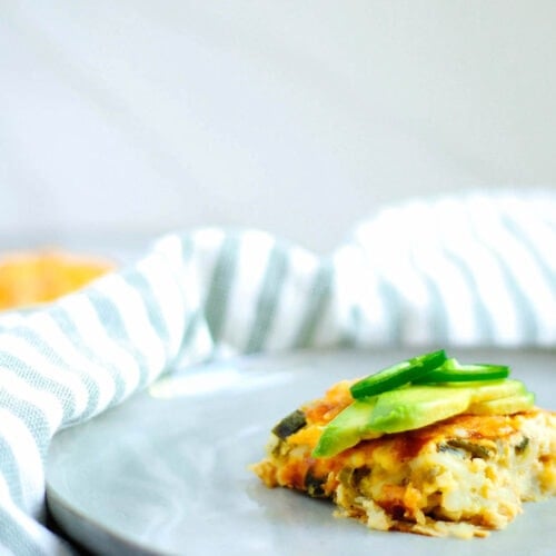 A meatless egg bake topped with avocado, served on a white plate.