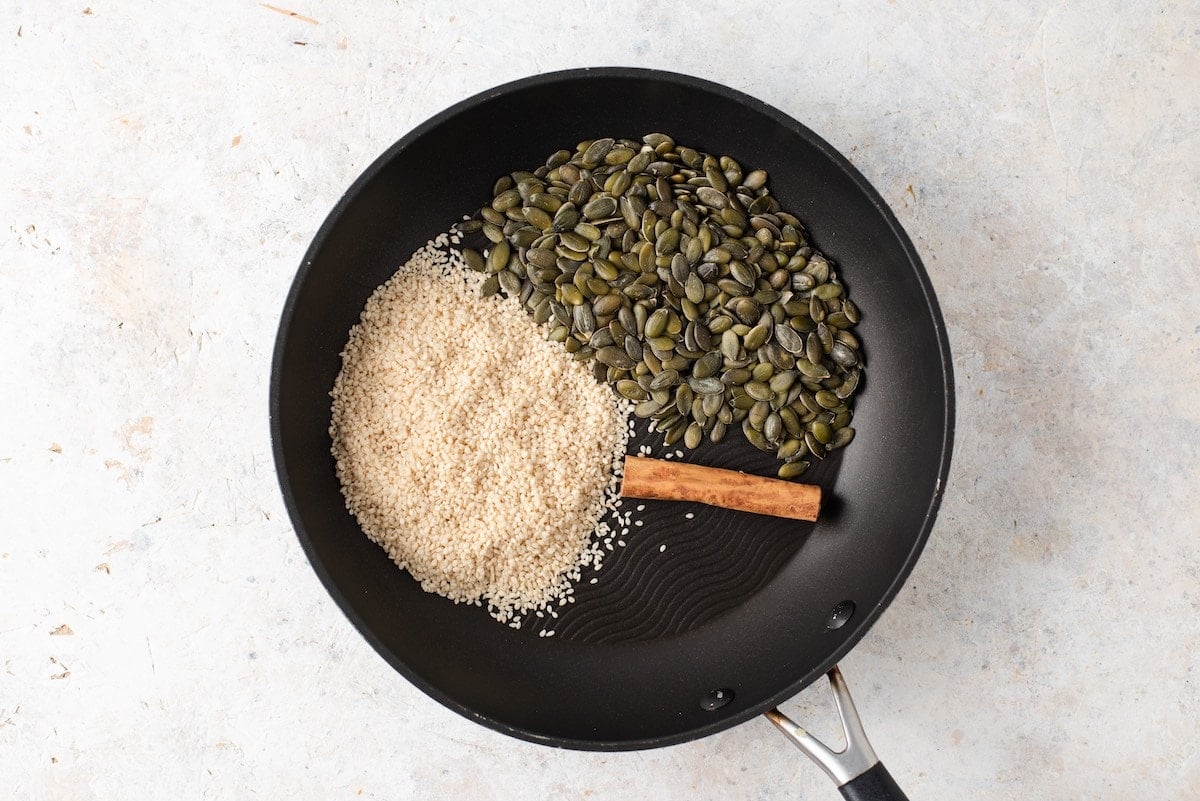 Pumpkin seeds, cinnamon and sesame seeds in a skillet. 