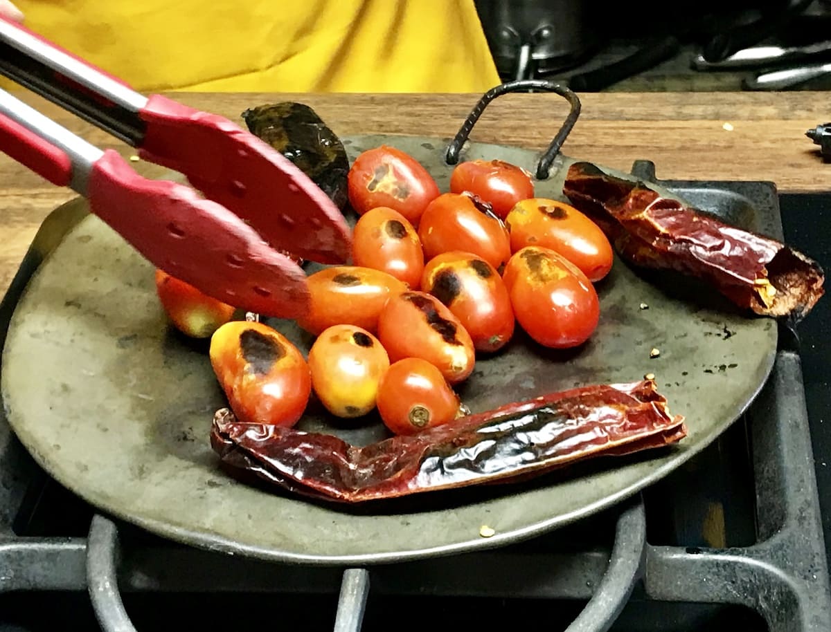 Tomaten und Guaque-Chili auf einem Comal in Guatemala verkohlen. To