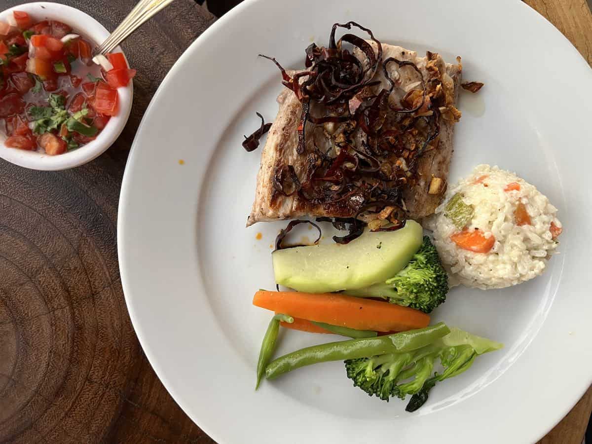 A grilled fish dinner with vegetables on a white plate in Mexico.