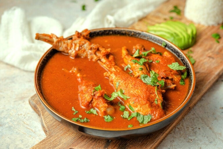 Kak ik Guatemalan turkey soup in a pottery bowl on a board.