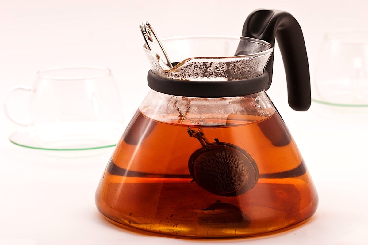 Black tea steeping in a clear glass pot.