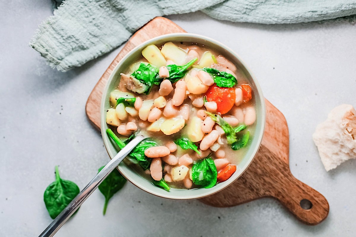 Vegan Spanish-style Caldo Gallego soup in a white bowl with a spoon.