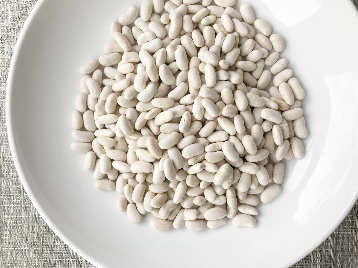 Dried white kidney beans in a white bowl.