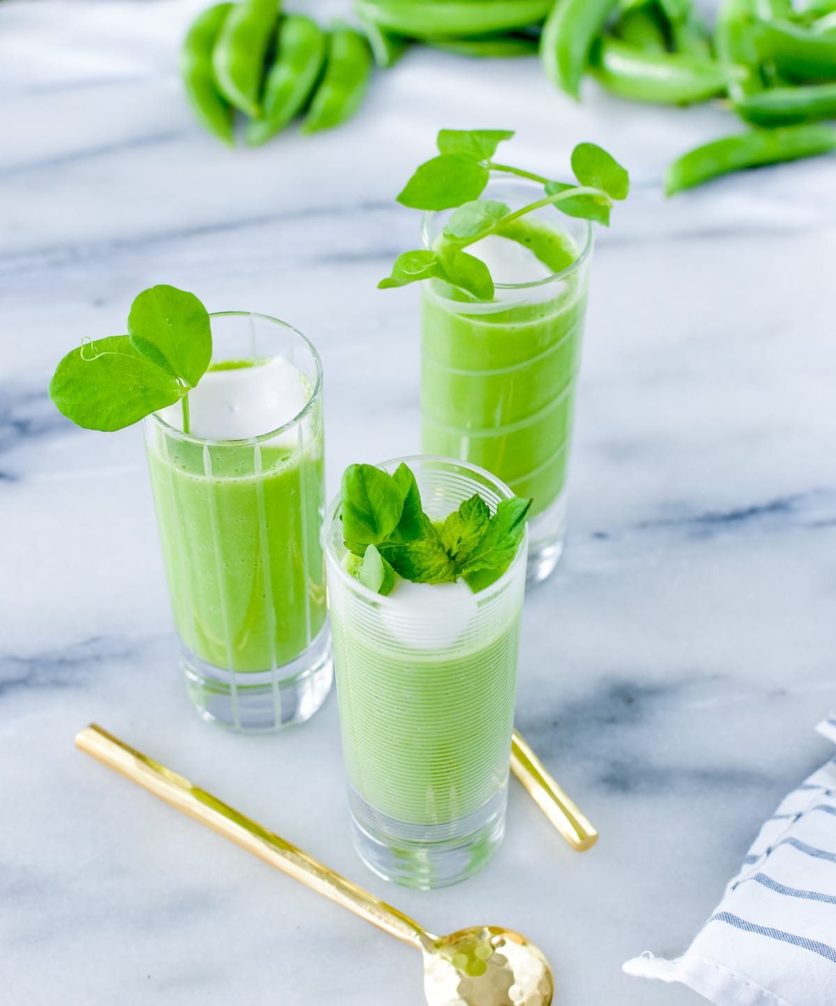 Three Spring Gazpacho in shooter glasses with a gold spoon.