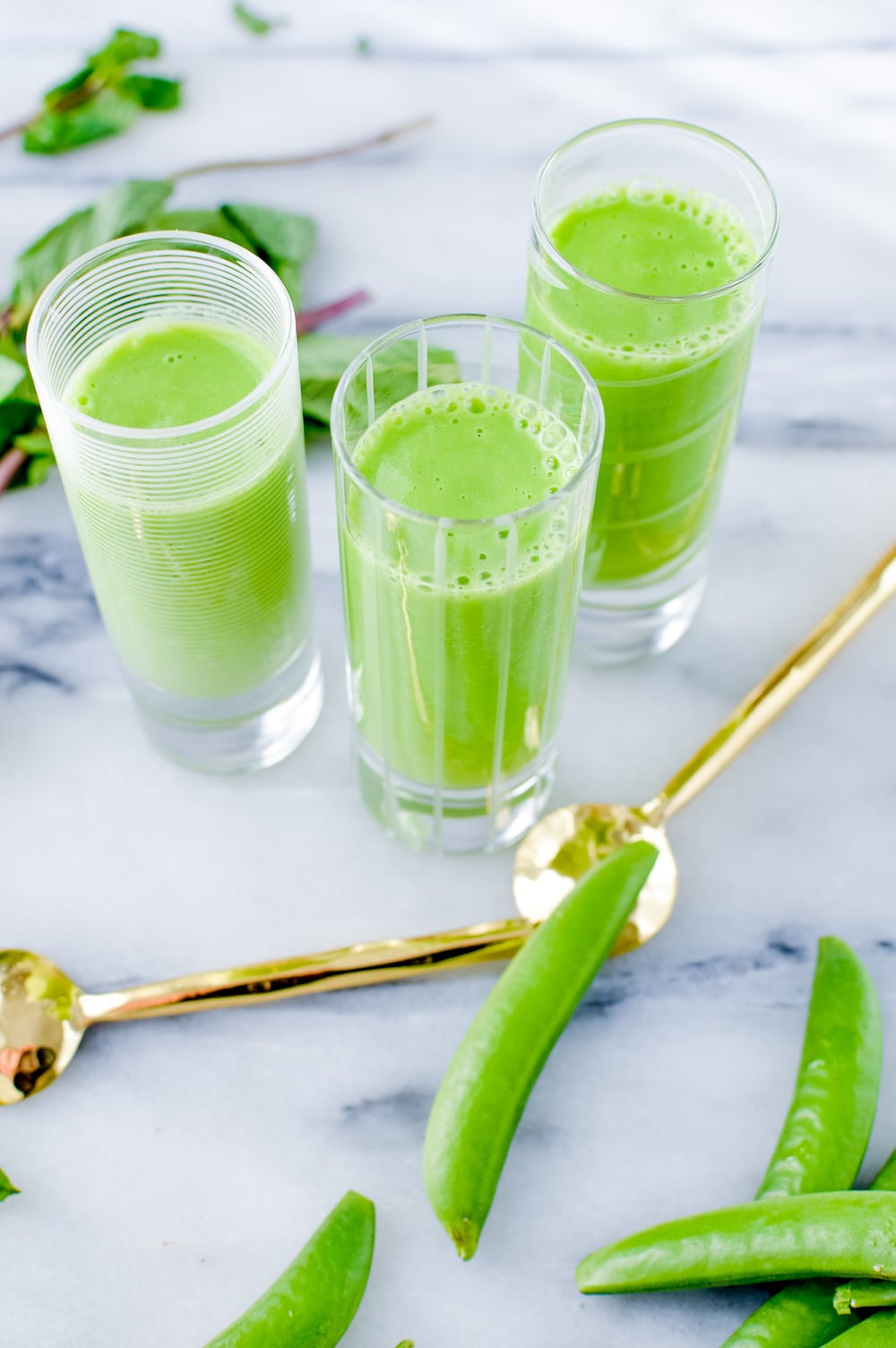 Chilled pea soup in shooter glasses on a marble table.