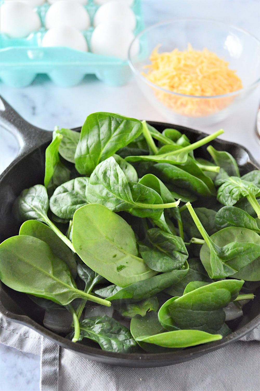 Spinach cooking in a skillet until wilted.